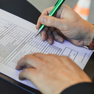  Persoon die een checklist invult op papier met een groene pen.